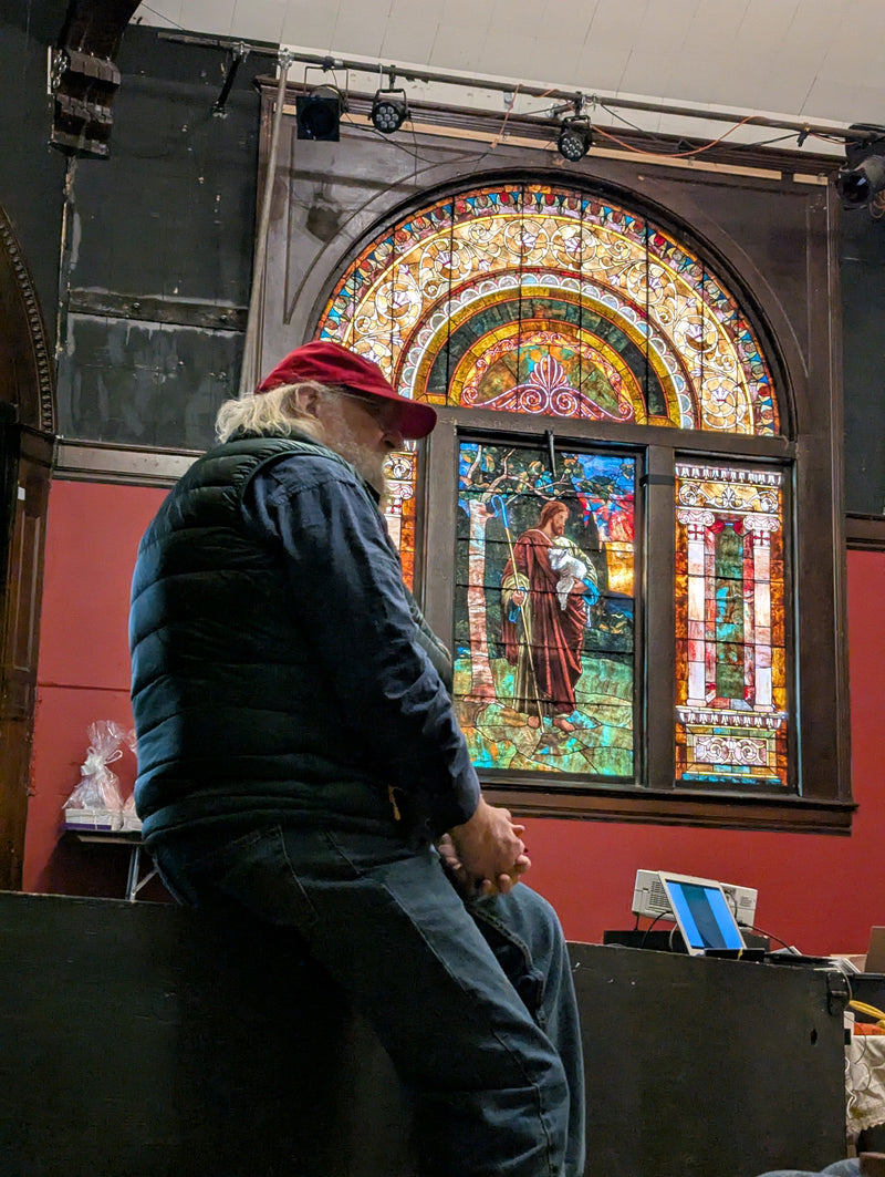 An attendee standing before a stained-glass window at the 2025 Fellowship of Preparation Makers gathering