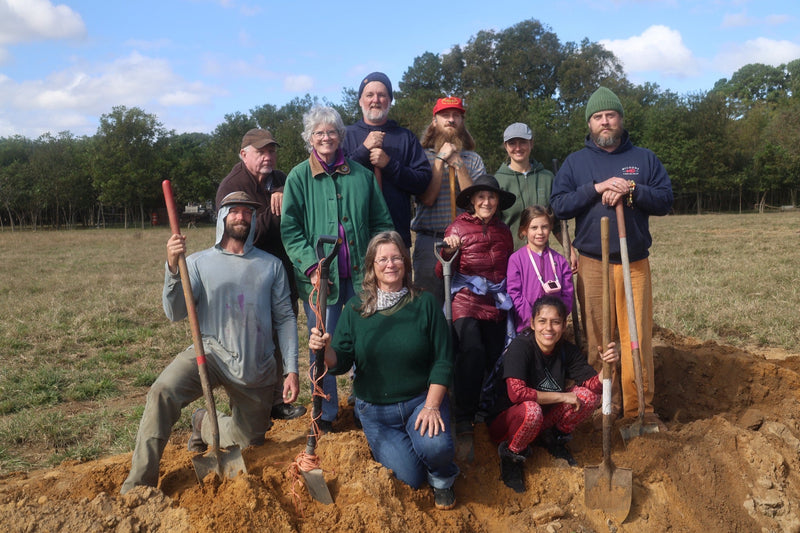 Workshop participants gathered outdoors with shovels.