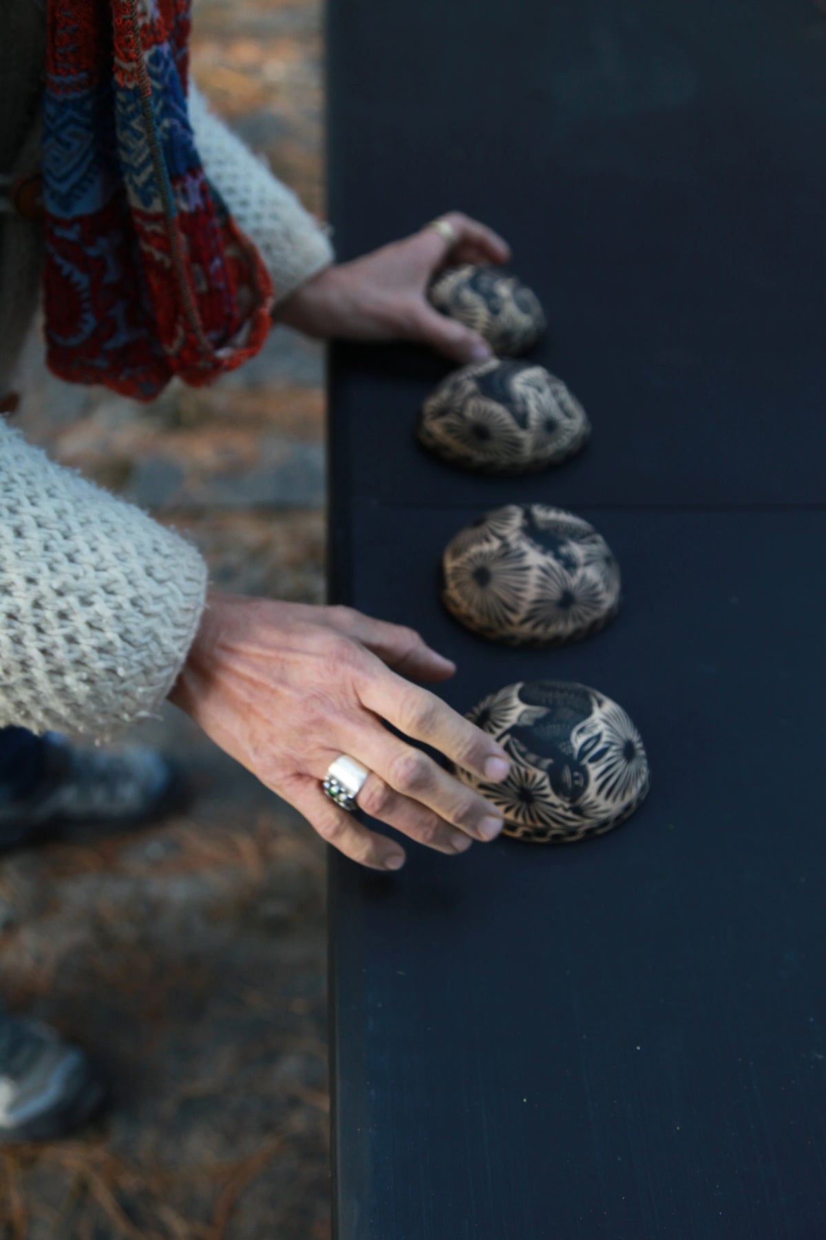 Hands arranging patterned earthen forms on a worktable