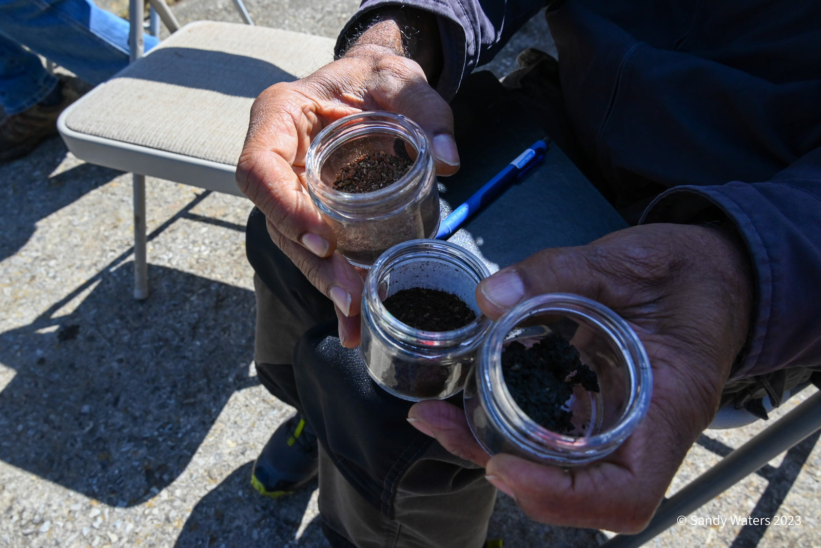 Hands holding biodynamic preparation samples in glass jars